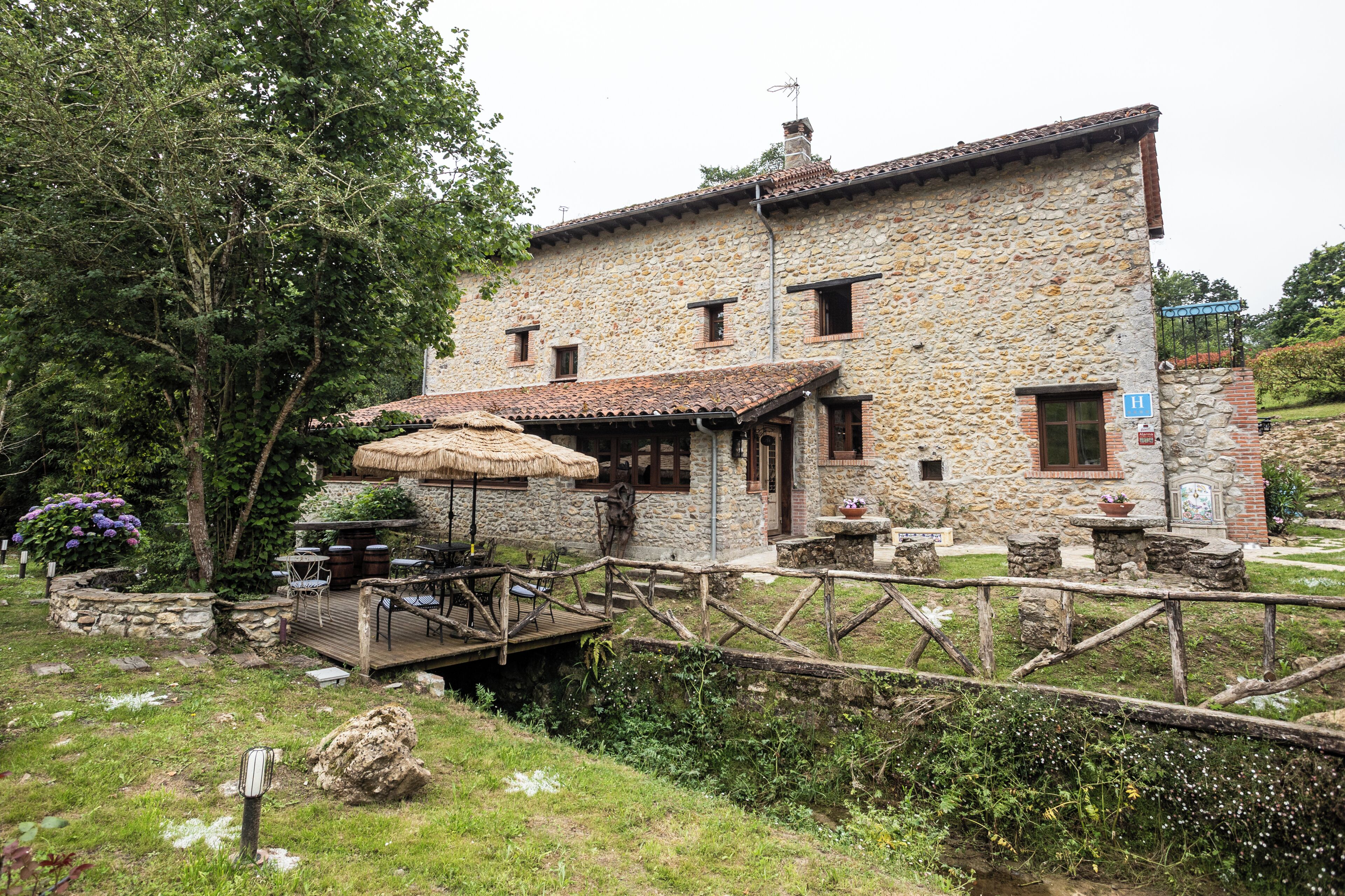 A stone building with a wooden deck, outdoor seating, and a small garden area.