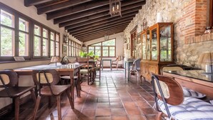 Un espace repas avec des tables et des chaises en bois, des murs en pierre et de grandes fenêtres.
