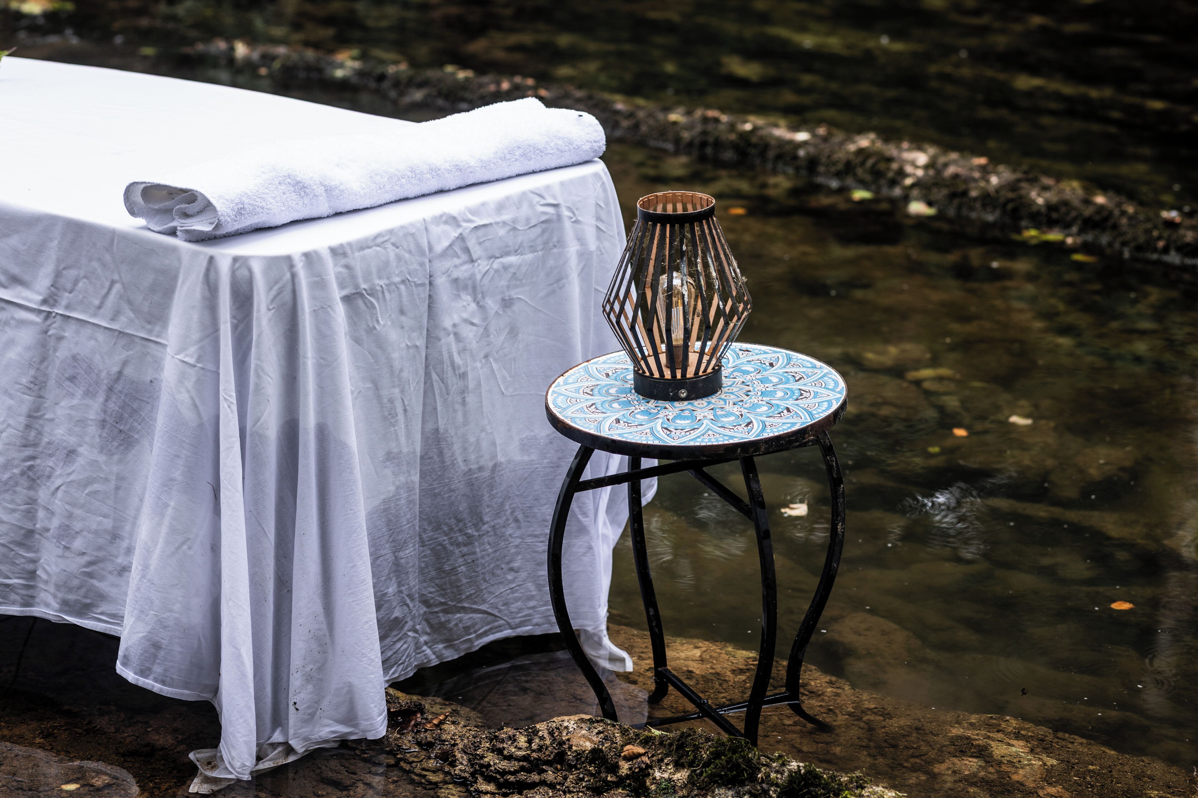 Una mesa con mantel blanco y una vela sobre un tablero redondo con diseño azul.