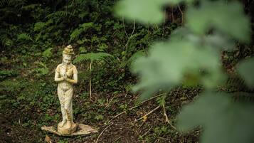 En statue i et naturligt landskab med frodig vegetation i baggrunden.