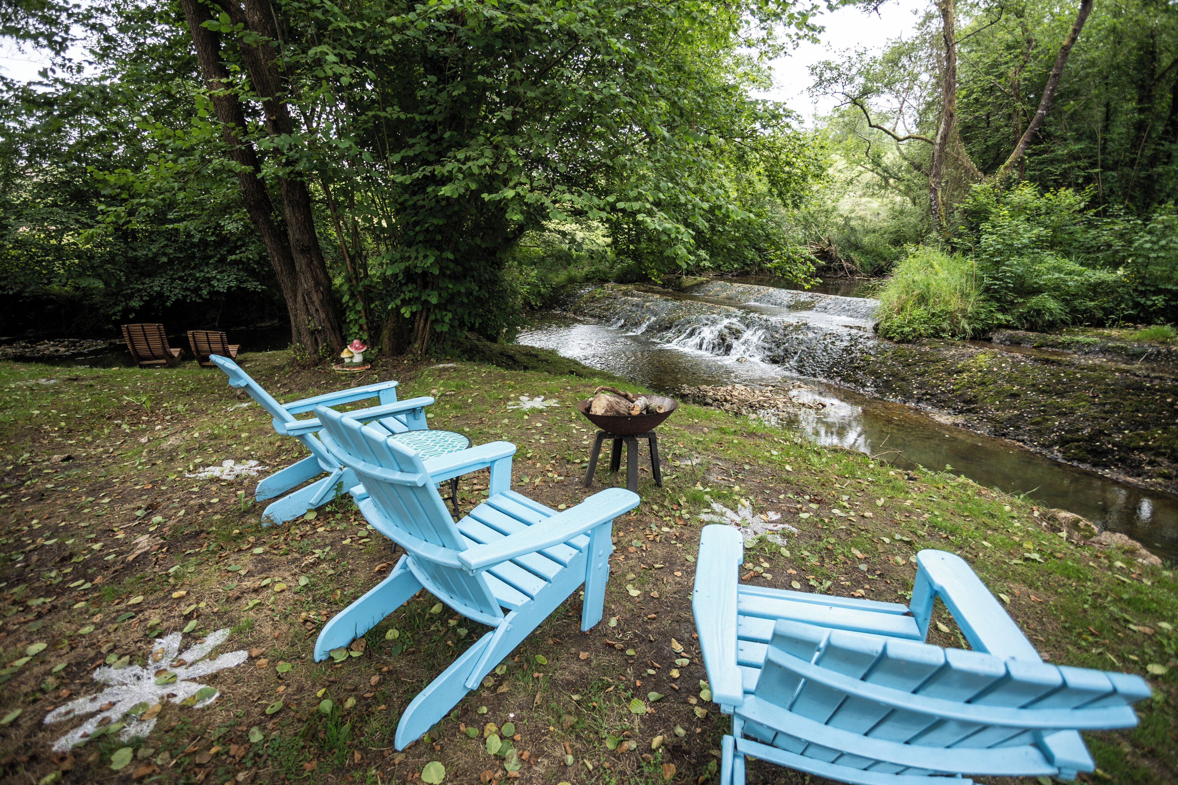 Terrasse extérieure avec vue sur un ruisseau et une forêt.