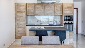 A modern kitchen with wooden cabinets, a stainless steel sink, and a built-in oven. - Penthouse Paradise in Qawra opposite the beach ! (St. Paul`s Bay)