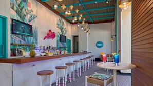 A bar area with a long counter, multiple stools, and a ceiling with hanging lights.