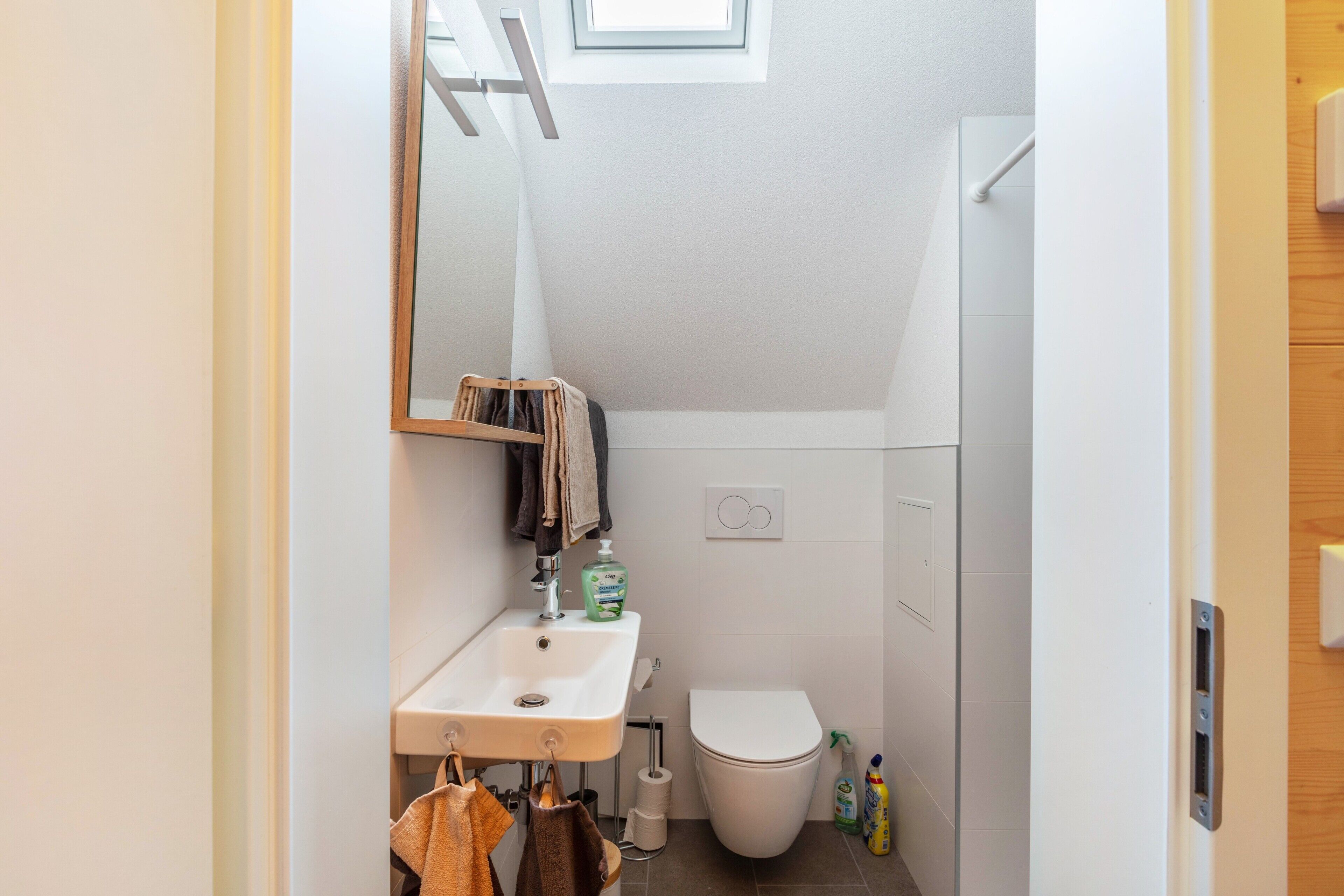 Een kleine badkamer met een wastafel, toilet en spiegel.