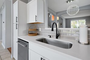 A modern kitchen with white cabinetry, a stainless steel sink, and a black faucet. - Family-Friendly 6BR Villa w/ Pool, Game Room (Kissimmee)