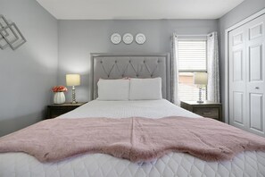 A bedroom with a bed, nightstands, a window with curtains, and wall decor. - Family-Friendly 6BR Villa w/ Pool, Game Room (Kissimmee)