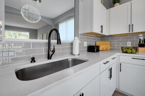 Eine moderne Küche mit einem großen Spülbecken, weißen Schränken und einer hängenden Leuchte.