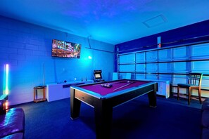 A pool table in a room with a large window and a mounted TV. - Family-Friendly 6BR Villa w/ Pool, Game Room (Kissimmee)