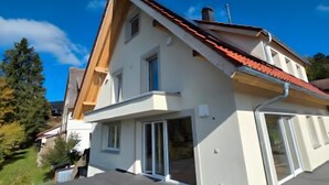 Een modern huis met twee verdiepingen, een schuin dak, grote ramen en een garage.