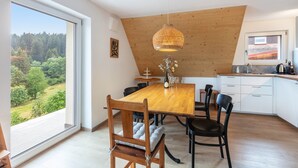 Een eetruimte met een houten tafel, stoelen en een hanglamp.