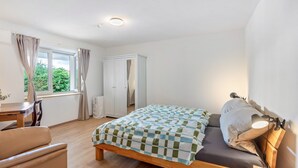 Een slaapkamer met een bed, bureau, stoel en kledingkast.
