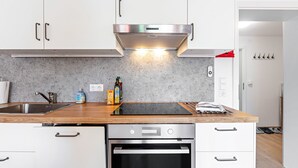 Een moderne keuken met witte kastjes, een roestvrijstalen afzuigkap, een dubbele spoelbak en een ingebouwde oven.