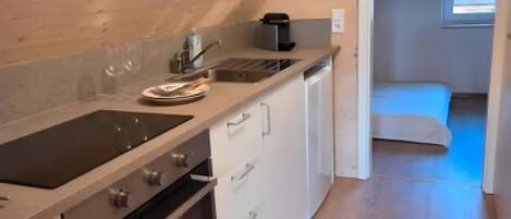 A kitchen with a built-in oven, a sink, and a coffee maker. There is a window with a view of the outside.