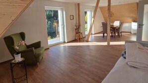 Een ruime kamer met een houten plafond, een eethoek en een groot raam.