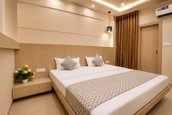Habitación de hotel con una cama grande, una mesita de noche, aire acondicionado instalado en la pared y una ventana con cortinas.