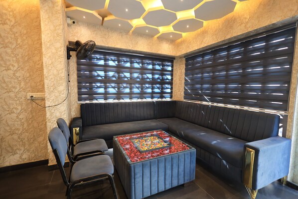 A modern lounge area with a sofa, chairs, and a central table with a colorful design. - Hotel Blue Mountain (Udaipur)