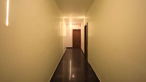 Un pasillo largo y estrecho con piso brillante y paredes, que conduce a una puerta al final.