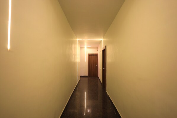 A long, narrow hallway with a shiny floor and walls, leading to a door at the end. - Hotel Blue Mountain (Udaipur)