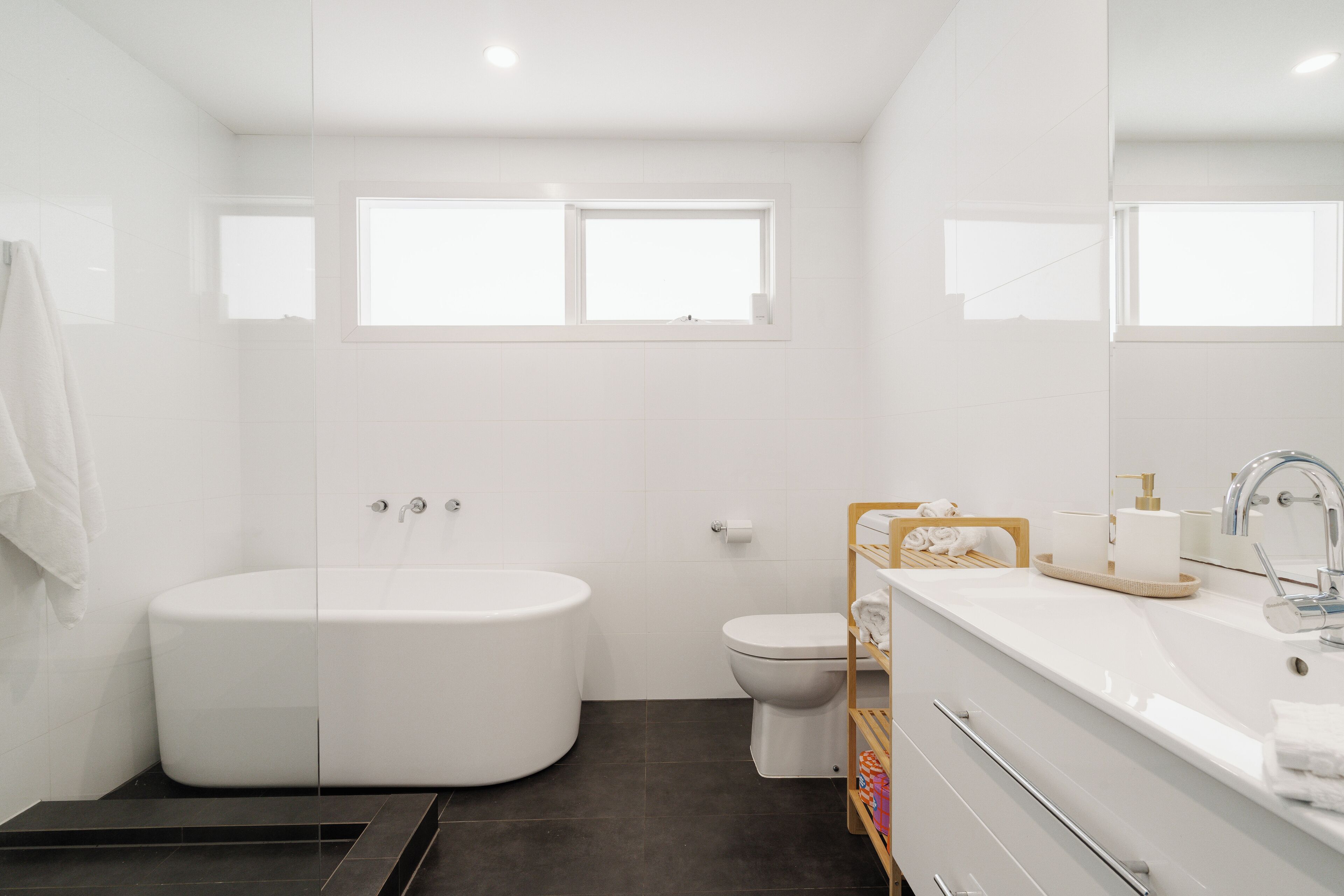 A modern bathroom with a bathtub, toilet, and a vanity with a mirror.