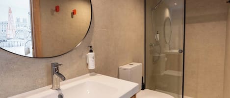 A modern bathroom with a large sink, toilet, and glass-enclosed shower.
