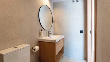 Ein modernes Badezimmer mit Toilette, Waschbecken und Spiegel.
