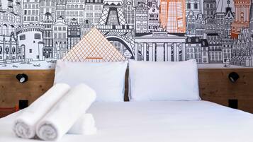 Un letto con lenzuola bianche, una testiera in legno e un murales con una vista sulla città.