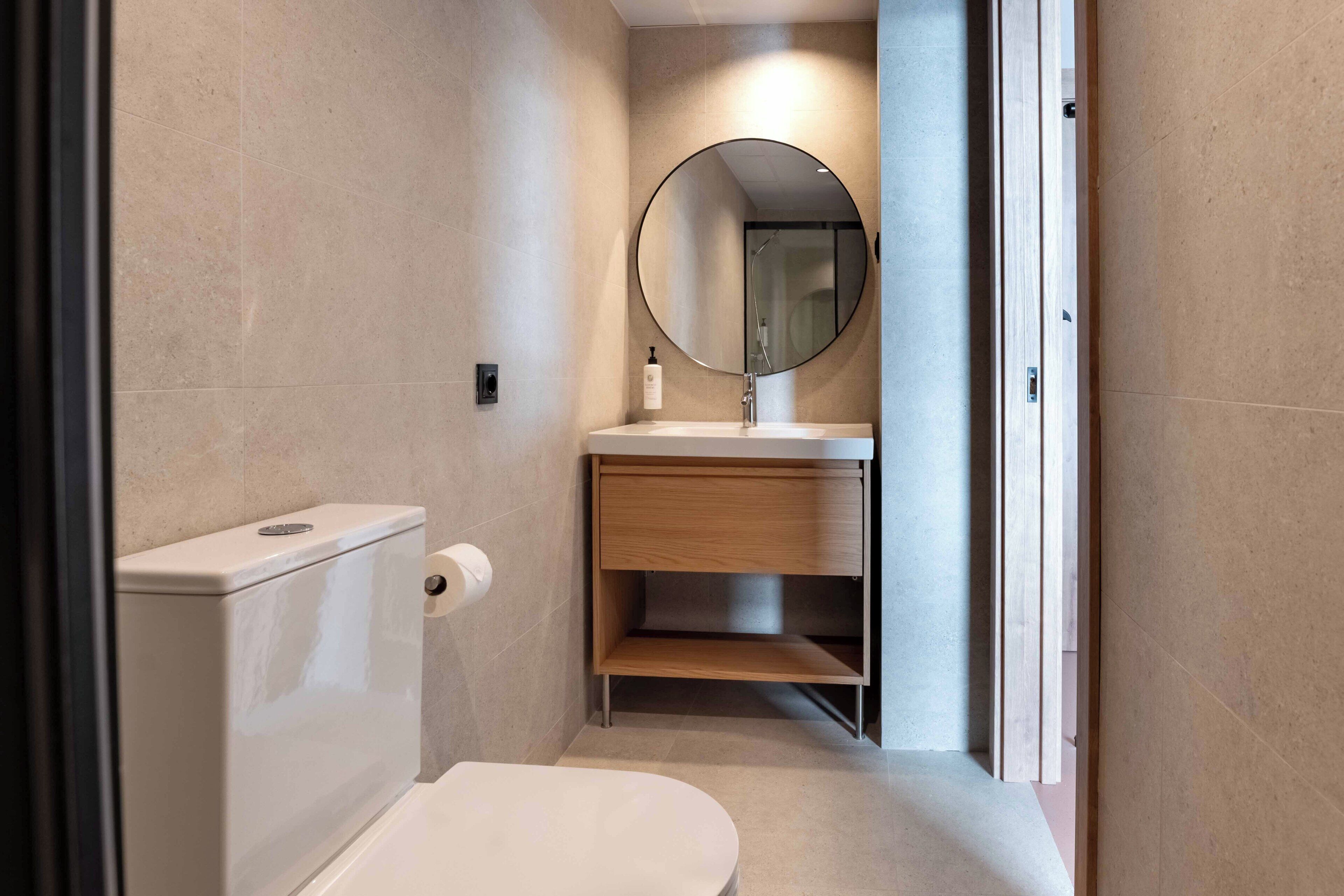 A modern bathroom with a toilet, sink, and mirror.