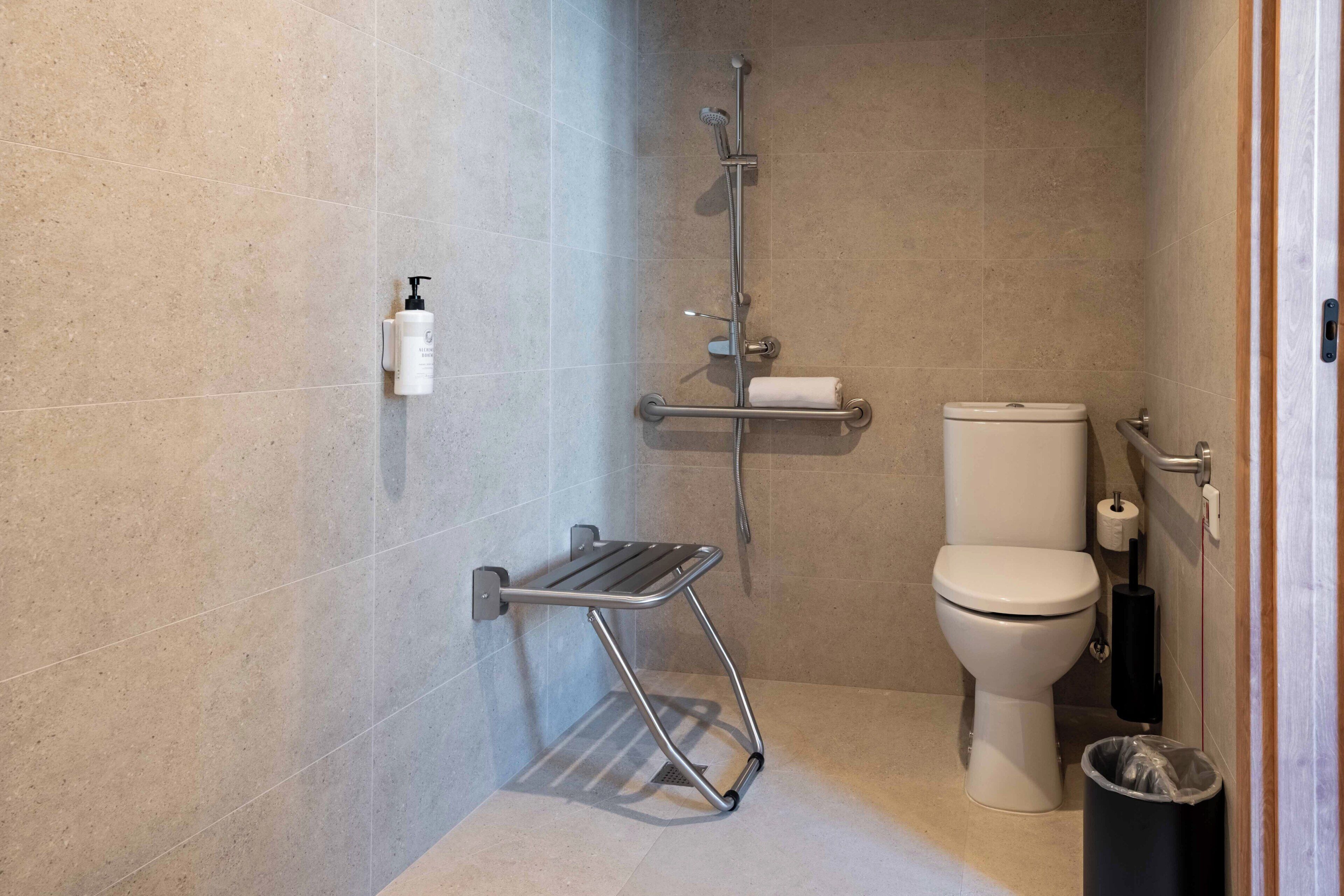 Un baño con ducha, inodoro y un pequeño cubo de basura.