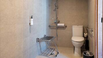 Un baño con ducha, inodoro y un pequeño cubo de basura.