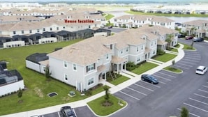 Zona residencial con casas separadas, estacionamiento y un cuerpo de agua al fondo.