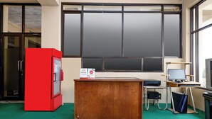 A room with a wooden desk, a red refrigerator, a computer setup, and large windows. - OYO 1706 Hotel H&w Solo (Jaten)