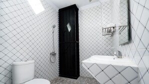 A modern bathroom with a toilet, a black shower enclosure, and a white sink with a diamond-patterned countertop. - OYO 1706 Hotel H&w Solo (Jaten)