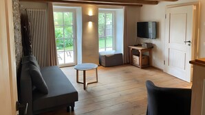 A room with a sofa, a small table, a television, and a door. - Apartment 'Ferienwohnung' with Private Garden and Terrace, Wi-Fi Included (Hüfingen)