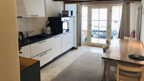 A kitchen with white cabinets, a black countertop, a microwave, and a coffee maker. - Apartment 'Ferienwohnung' with Private Garden and Terrace, Wi-Fi Included (Hüfingen)