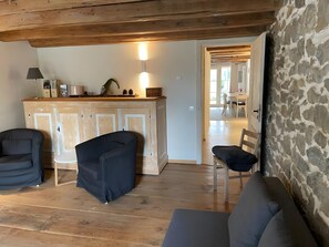 Une pièce avec un plafond en bois, un mur en pierre, un meuble en bois et un coin salon comprenant des chaises et un canapé.