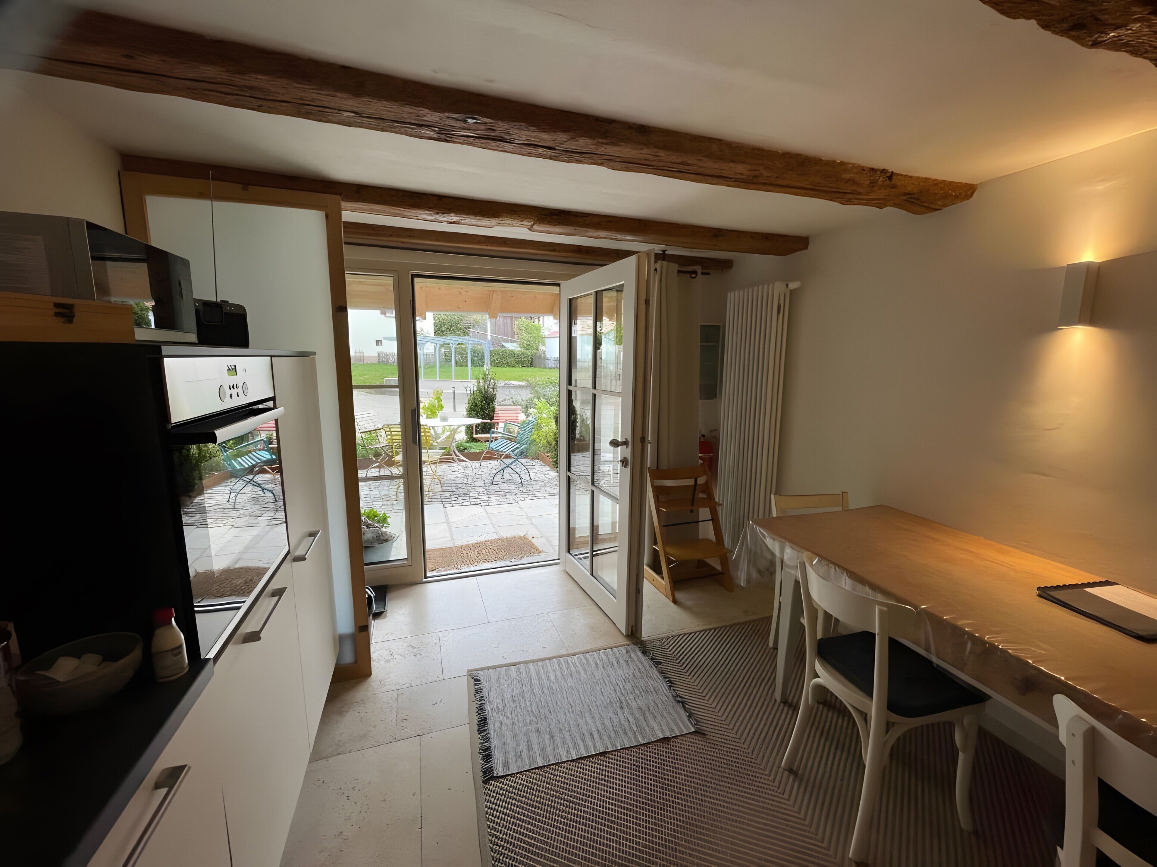 A compact kitchen with a refrigerator, a dining table with chairs, and a sliding glass door leading to an outdoor patio.