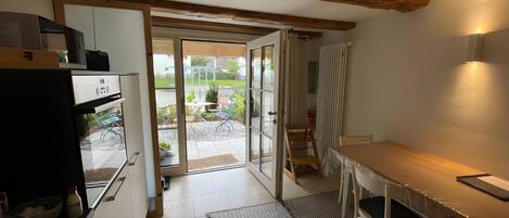 A compact kitchen with a refrigerator, a dining table with chairs, and a sliding glass door leading to an outdoor patio.