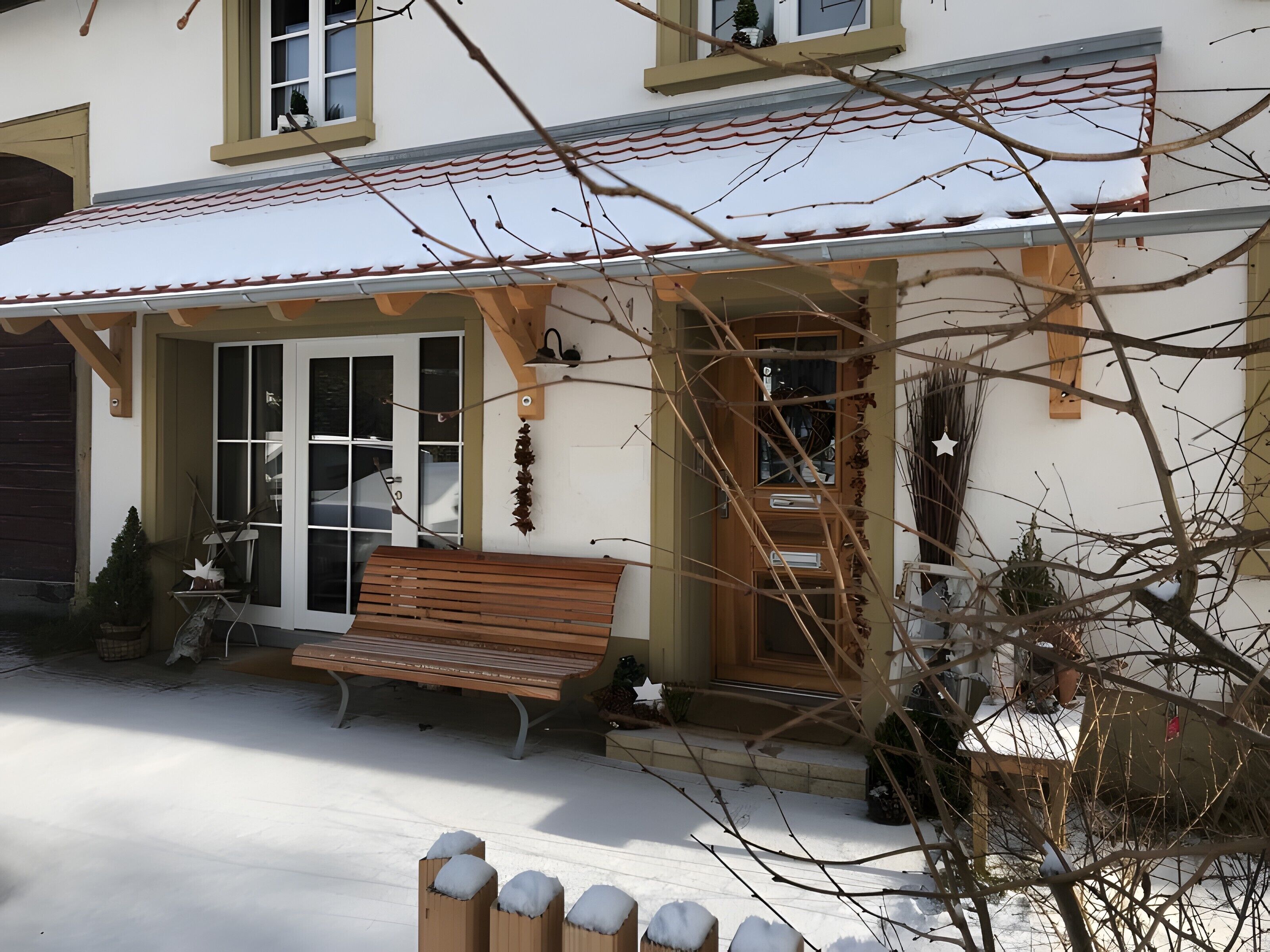 Een huis met een overdekte veranda, een bank en een deur naar binnen.