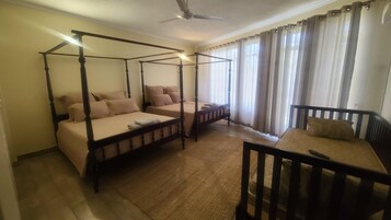 Una habitación con cama con dosel, una cama individual, una silla de madera y una pequeña mesa.