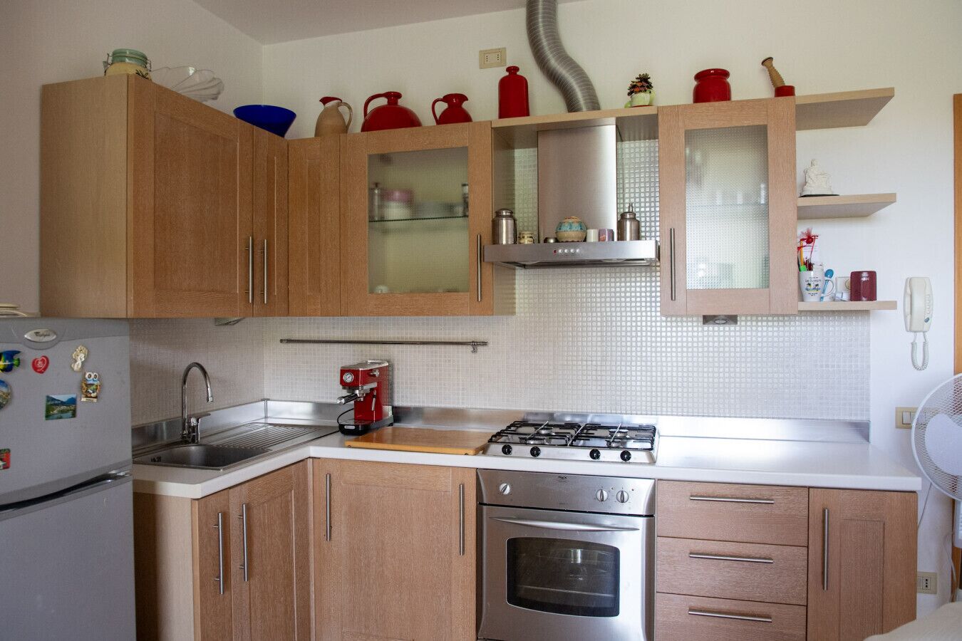 Une cuisine avec des meubles de rangement en bois, une cuisinière à gaz, un four, un évier et une machine à café.