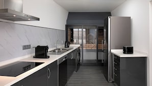 Una cocina moderna con encimera negra, electrodomésticos de acero inoxidable y horno integrado.