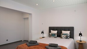 Una habitación de hotel moderna con una cama grande, dos mesitas de noche e iluminación empotrada en el techo.