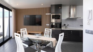 Una cocina moderna con un televisor de pantalla plana grande, horno empotrado y armarios de acero inoxidable.
