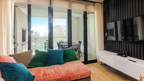 Una sala de estar moderna con sofá, televisor y puertas corredizas de vidrio que dan a un espacio exterior.