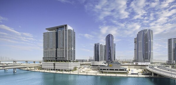 A modern cityscape with high-rise buildings, a bridge, and a waterfront. - LUX The Voleo Canal View Suite (Dubai)
