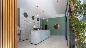 A reception area with a marble counter, clocks, and pendant lighting. - The NEO two room Suite N302 by MaRKoS (Gudauri)