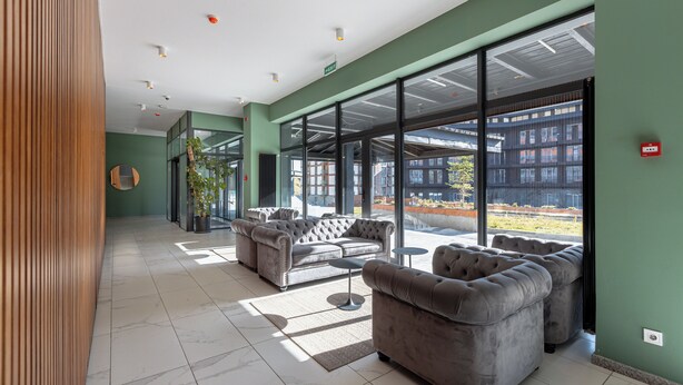 A modern lobby with grey sofas, a coffee table, and a large window offering a view of the outside. - The NEO two room Suite N302 by MaRKoS (Gudauri)