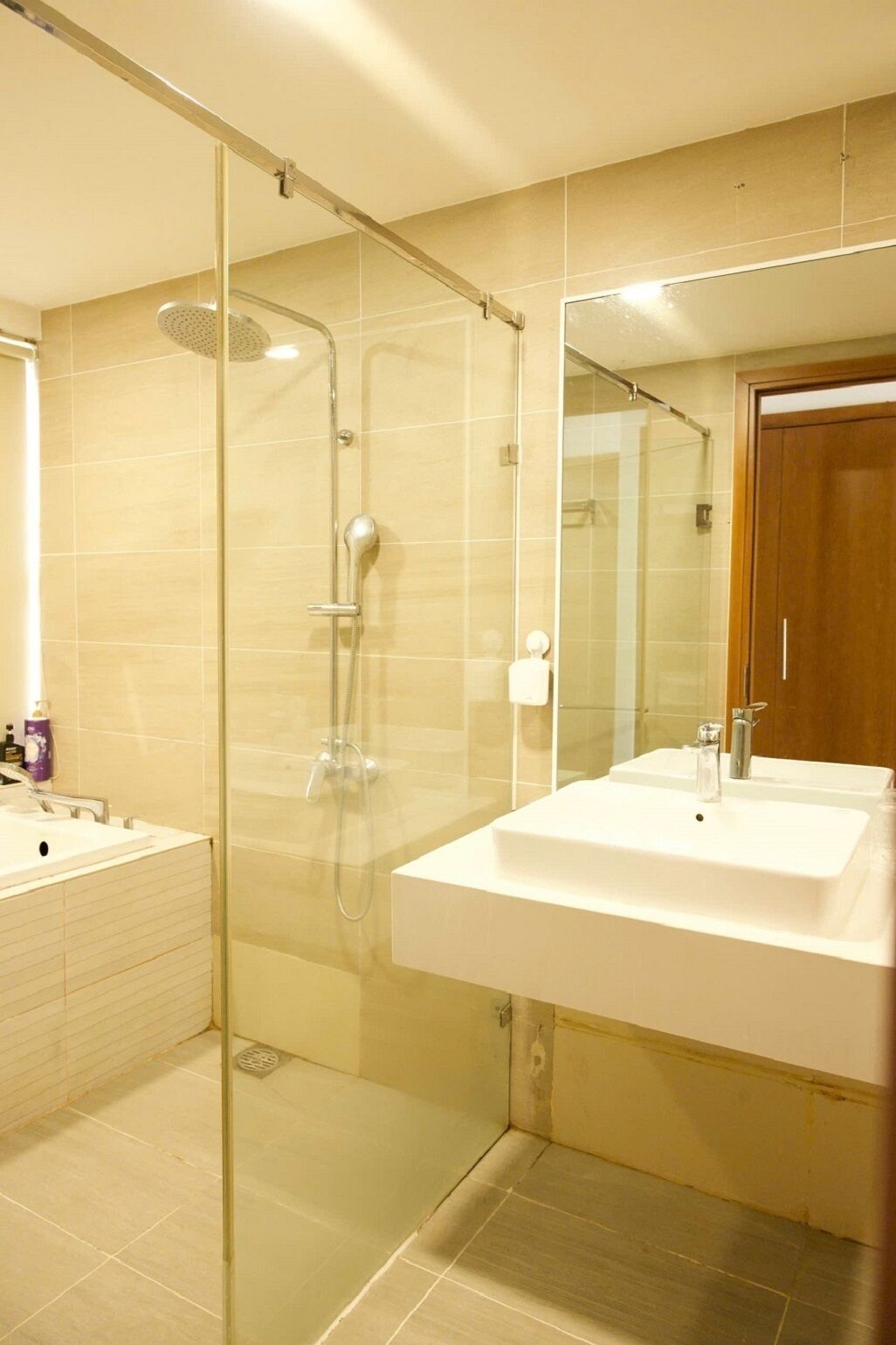Un baño moderno con ducha de vidrio, un espejo grande y un lavabo blanco.