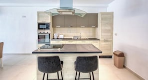 A modern kitchen with a central island, two bar stools, and a built-in oven. - Spacious 3BR in Qawra w/ Balconies & Coastal Vibe (St. Paul`s Bay)