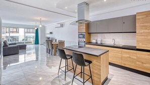 Una cocina moderna con una isla central, taburetes de bar y un comedor con mesa y sillas.